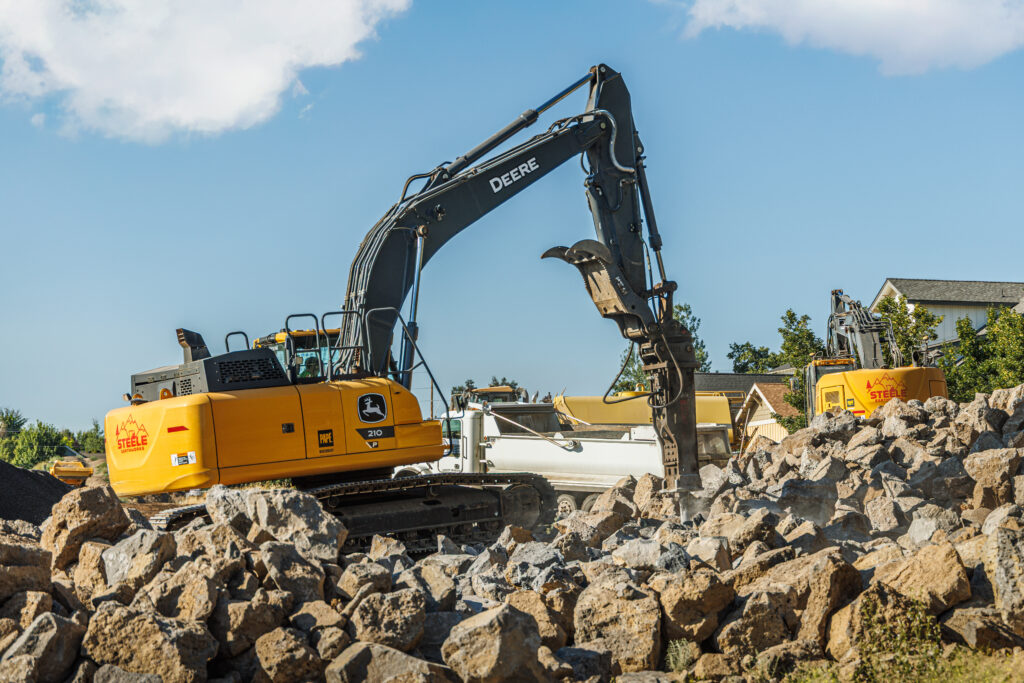 heavy equipment brush rakes attachment clearing debris from wet ground during site cleanup