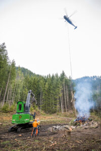 Forestry equipment reducing wildfire fuel loads during peak fire season to help protect forests, property, and access roads