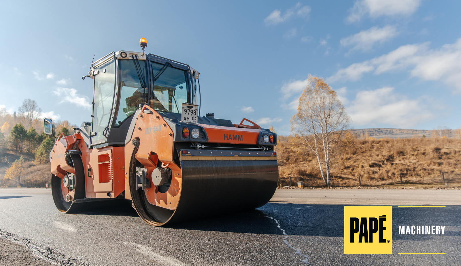 HAMM HD140 tandem asphalt roller compacting newly paved asphalt during a road construction project.